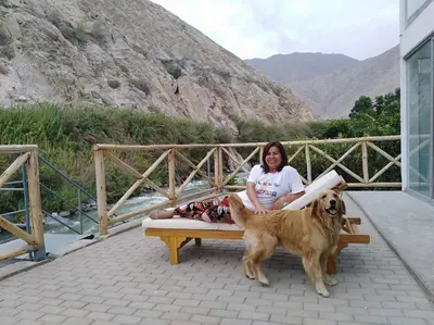a woman sitting on a bench next to a dog at San Jerónimo River Lodge in Lunahuaná