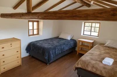 a bedroom with a bed and a dresser and two windows at Refugio tierra viva in Cusco