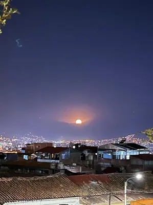 a view of a city at night with the moon at Apartamento Salkantay con vista al Cusco in Cusco