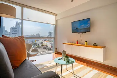 a living room with a couch and a large window at Platino Apartments by Vibrant in Lima