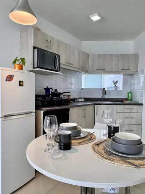 a kitchen with a table and a white refrigerator at Alojamiento moderno San Isidro Pet Friendly in Lima