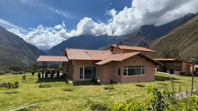 a house in a field with mountains in the background at Urubamba Luxury Stay 