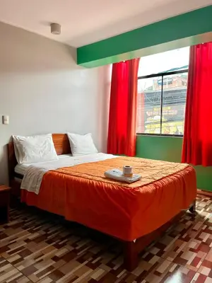 a bedroom with a bed with red curtains and a window at Hotel PRADO'S in Satipo