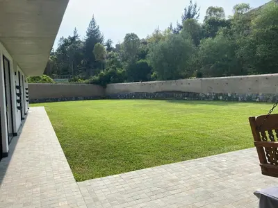 a large grassy yard with a wall and a bench at Casa de Campo en Cieneguilla in Cieneguilla