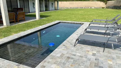 a swimming pool with two chairs and a table at Casa de Campo en Cieneguilla in Cieneguilla