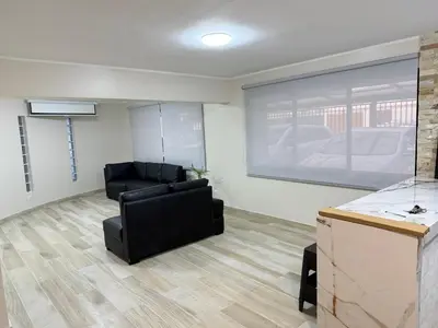 a living room with a black chair and a large screen at Minidepartamento en Miraflores in Lima
