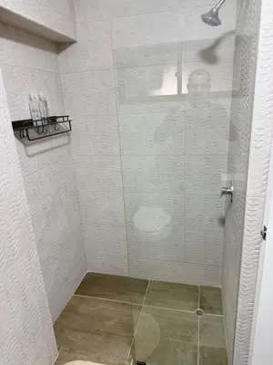a shower stall with a glass door with a person reflection at Minidepartamento en Miraflores in Lima
