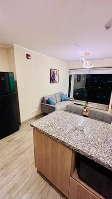 a kitchen and living room with a couch and a counter at 1 dormitorio moderno con balcon a 5 min de parque Kennedy-Miraflores in Lima