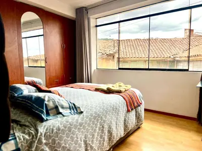 a bedroom with a bed and a large window at Departamento a 5 cuadras de la Plaza de Armas Cusco in Cusco