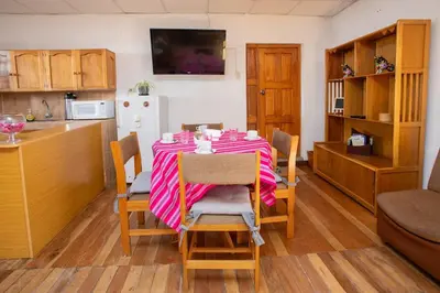 a dining room with a table and a kitchen at Departamento a 2 cuadras de la Plaza de Armas in Cusco