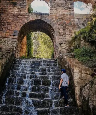 a man sitting on a stone stairs next to a waterfall at Departamento a 2 cuadras de la Plaza de Armas in Cusco