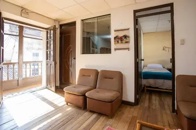 a room with a chair and a bed and a window at Departamento a 2 cuadras de la Plaza de Armas in Cusco