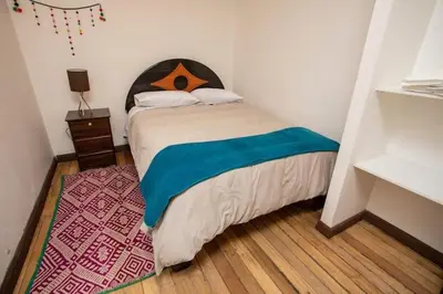 a bedroom with a bed with a wooden headboard at Departamento a 2 cuadras de la Plaza de Armas in Cusco