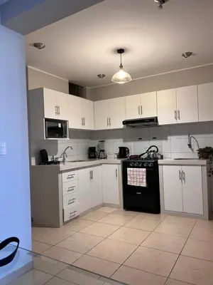 a kitchen with white cabinets and a black stove top oven at Misi House Hostal in Lima