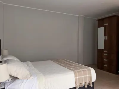 a bedroom with a white bed and a dresser at Misi House Hostal in Lima