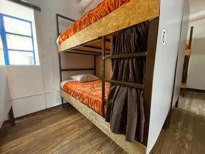 a bedroom with a bunk bed with orange sheets at Hostel - Cusco Dorms in Cusco