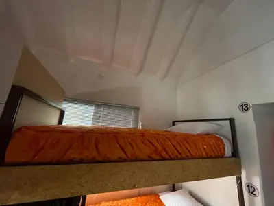 a bunk bed with an orange comforter in a room at Hostel - Cusco Dorms in Cusco