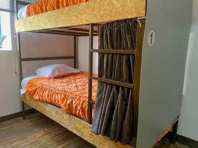 a bunk bed in a room with an orange bed at Hostel - Cusco Dorms in Cusco