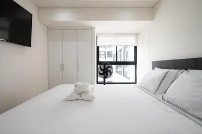 a white bedroom with a teddy bear sitting on a bed at Aquilarias Apartments by Vibrant in Lima