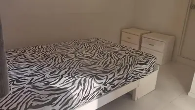 a zebra print bed in a white bedroom at DEPARTAMENTO AMOBLADO POR TEMPORADA DE PLAYA En PUNTA HERMOSA in Punta Hermosa