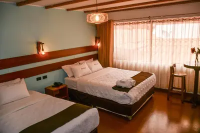 a hotel room with two beds and a window at Hotel Boutique MIRANDO AL SOL in Ollantaytambo