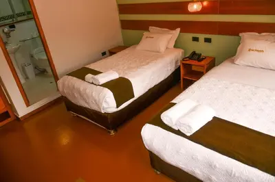 a room with two beds and a bathroom with a shower at Hotel Boutique MIRANDO AL SOL in Ollantaytambo