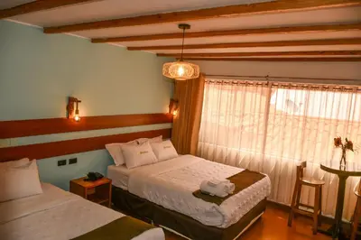 a hotel room with two beds and a window at Hotel Boutique MIRANDO AL SOL in Ollantaytambo