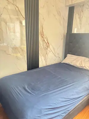 a bed in a room with a marble wall at Habitación privada en departamento compartido in Lima