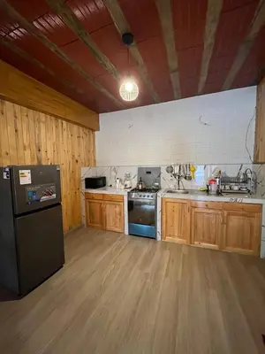 a kitchen with wooden cabinets and a black refrigerator at Hassinger Haus in Oxapampa