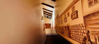 a hallway with paintings on the walls of a building at PLAZA cusco Amankay in Cusco