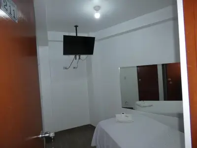 a white room with a bed and a tv on the wall at Hotel Lima Norte in Carabayllo