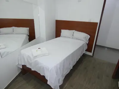 a small bedroom with two beds and a mirror at Hotel Lima Norte in Carabayllo