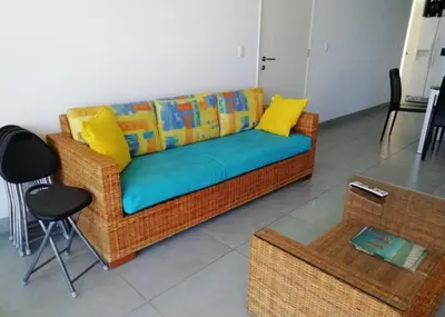 a wicker couch with yellow pillows in a living room at Paracas Exclusivo Departamento familiar in Pisco