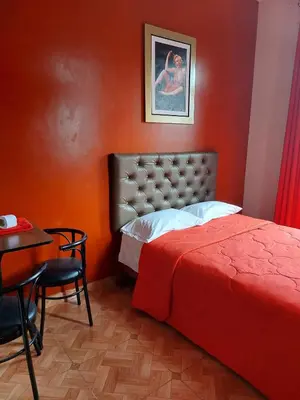 a bedroom with a red wall with a bed and a table at Anciejo inn ll in Lima