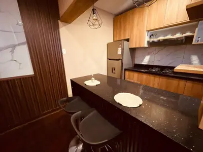 a kitchen with a counter with stools and a refrigerator at Estancia Ideal in Lima
