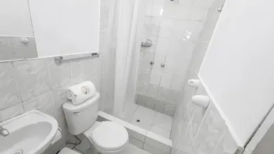 a white bathroom with a toilet and a shower at Casona MICA'S HOUSE in Cusco