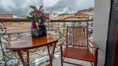 a table and a chair on a balcony with a vase of flowers at Casona MICA'S HOUSE in Cusco