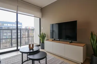 a living room with a flat screen tv on a white cabinet at Larco by Wynwood House in Lima