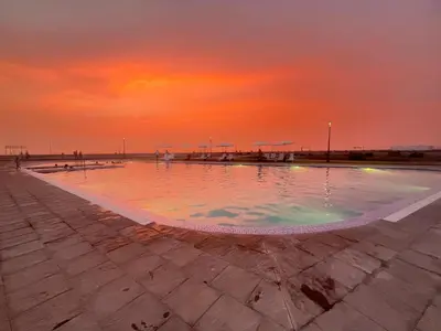 a swimming pool with a sunset in the background at Chincha CasaLed y jacuzzis sol todo el año in Tambo de Mora