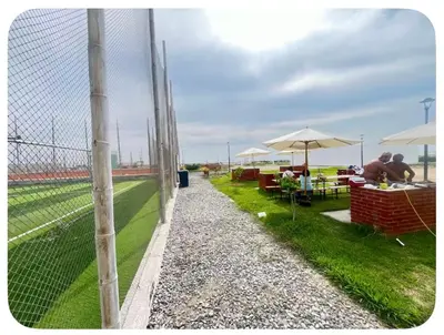a fence next to a field with tables and umbrellas at Chincha CasaLed y jacuzzis sol todo el año in Tambo de Mora