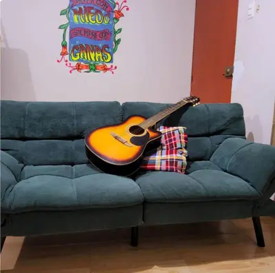 a guitar sitting on top of a blue couch at Casa hogareña Pequeña in Ica