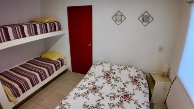 a small room with a bed and a red door at Paradice a 30 minutos del Boulevar de Asia