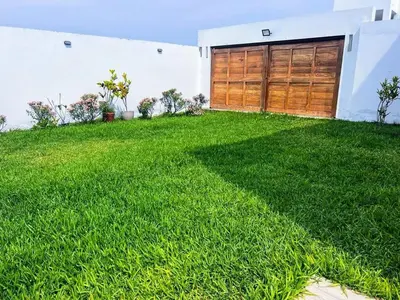 a yard with green grass and a garage at Paradice a 30 minutos del Boulevar de Asia
