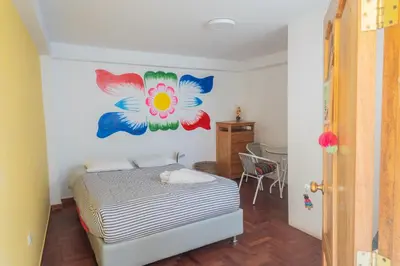 a bedroom with a bed with a flower painting on the wall at Room B Stylish Matrimonial Room for a Comfortable Stay in Cusco