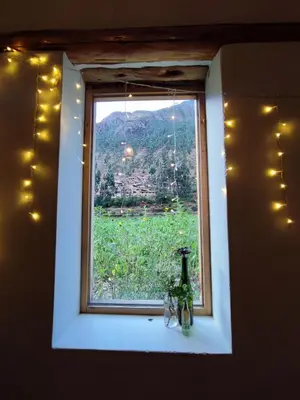 a window with a bottle on a ledge with a view at Loft acogedor in Ollantaytambo
