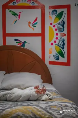 a bed with a wooden head board with colorful paintings at Room D Comfort Family Suite Near Historic Cusco in Cusco