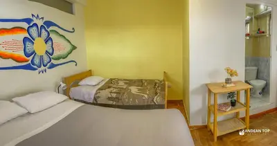 a bedroom with two beds and a painting on the wall at Room E Warm and Practical Room for Families or Friends in Cusco