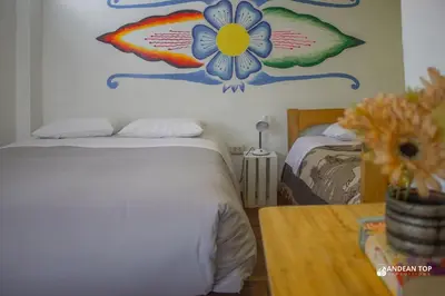 a bedroom with a bed with a flower on the wall at Room E Warm and Practical Room for Families or Friends in Cusco