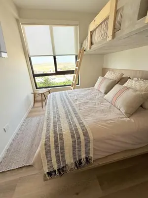 a bedroom with a bunk bed with a ladder at Paracas Navigare 2 BD Vista Reserva y Mar Último piso Terraza Kamado BBQ in Santo Domingo