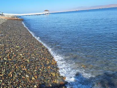 a beach with rocks and water and a pier at Paracas Exclusivo Departamento familiar in Pisco